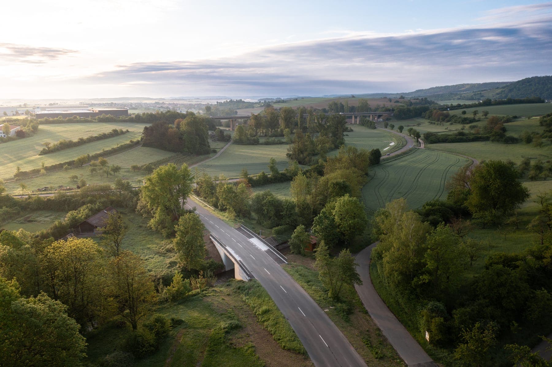 Straßenbrücke in hügeliger Landschaft im Morgenlicht